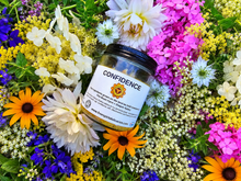 Load image into Gallery viewer, Confidence botanical soy candle surrounded by farm flowers