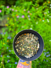 Load image into Gallery viewer, Pain + Inflammation Relief Tea Tonic herbal blend held over the Wild Indigo Forest Farm garden