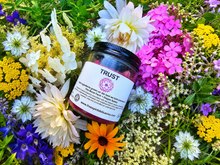 Load image into Gallery viewer, Trust botanical soy candle surrounded by farm flowers
